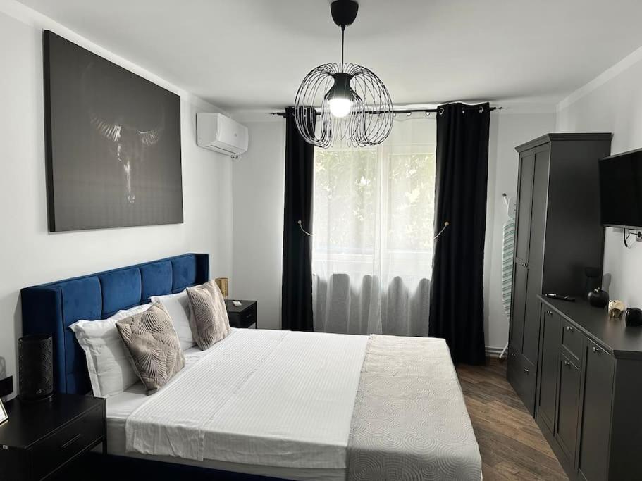 a bedroom with a large bed with a blue headboard at Priveé Residence in Caransebeş