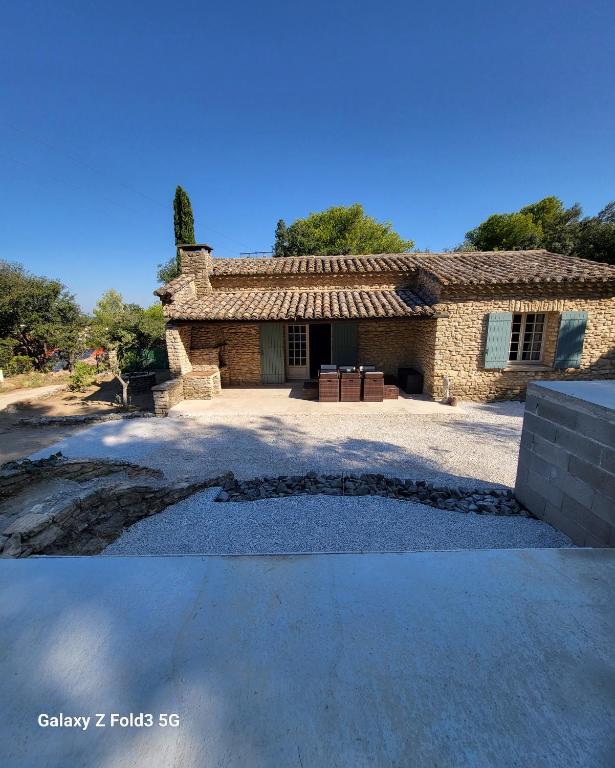 une grande maison en pierre avec une allée en face de celle-ci dans l'établissement maison au cœur de la colline, à Cavaillon