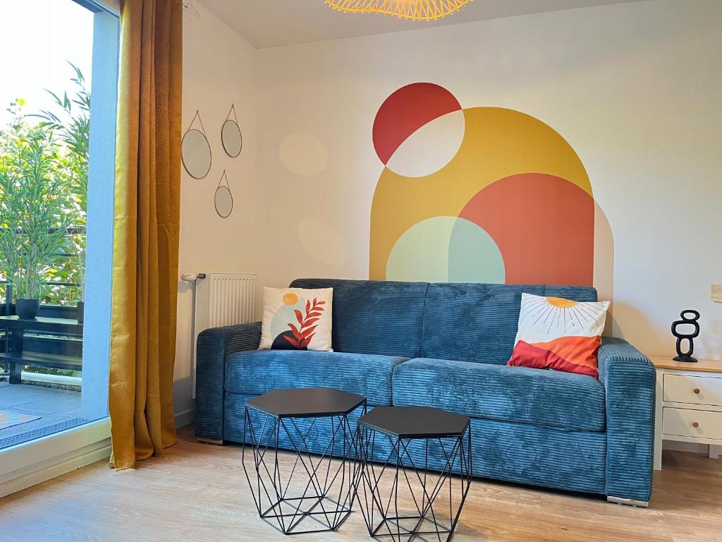 ein Wohnzimmer mit einem blauen Sofa und 2 Hockern in der Unterkunft Le 24 Nautic, Appartement douillet Bassin olympique Disneyland & Paris avec parking in Vaires-sur-Marne