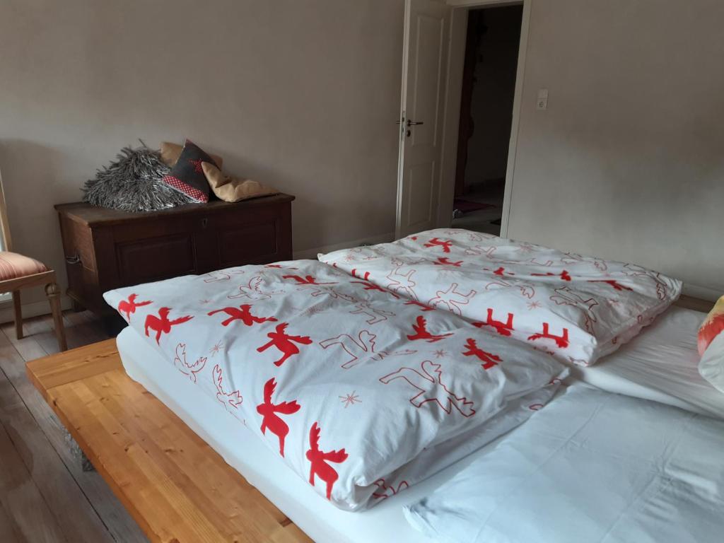 a bed with a white blanket with red horses on it at Ales Ursula Sokolowski in Zerf