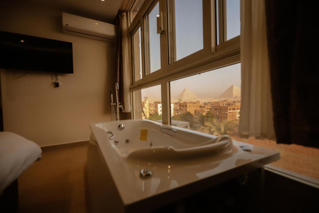 King Khafren View INN في القاهرة: حوض استحمام في غرفة مع نافذة