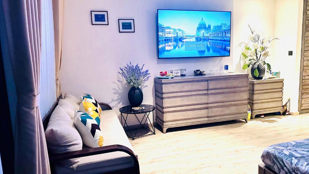 Apec Mandala Phú Yên View Biển في توي هوا: غرفة معيشة مع أريكة وتلفزيون على الحائط