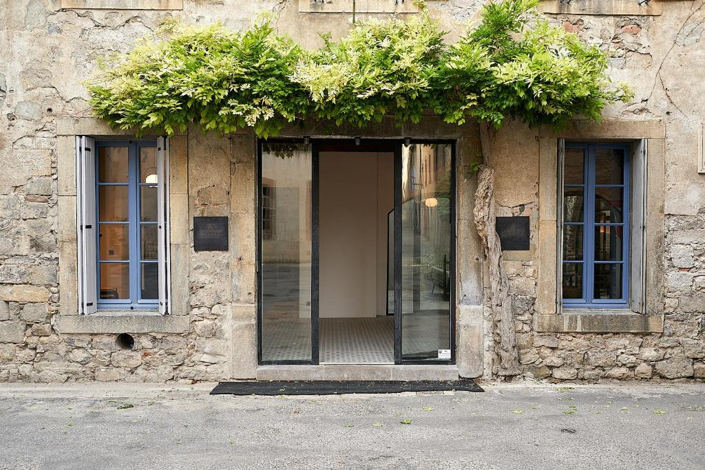 un edificio con dos ventanas con plantas. en Bouquerie Lagrasse, en Lagrasse