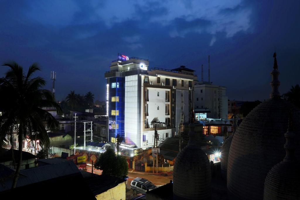 um grande edifício branco com luzes acesas à noite em Hotel Blue Bird, Nagaon em Nowgong