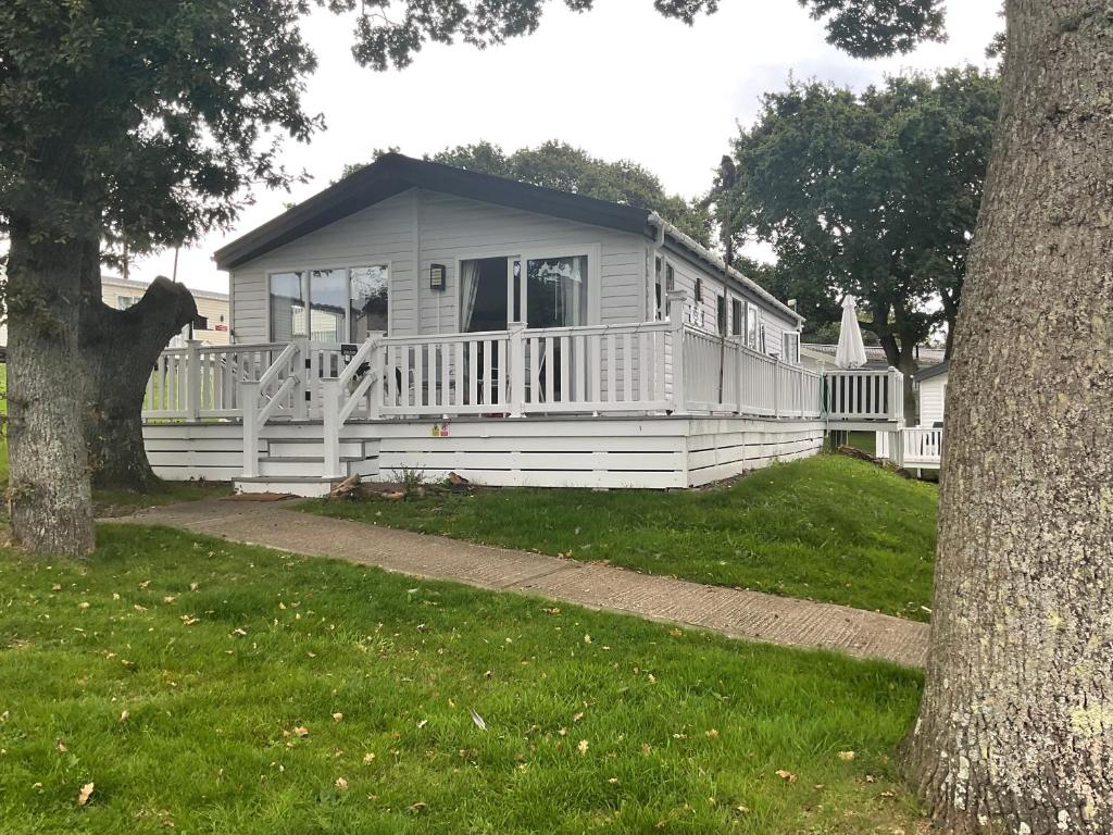 a white house with a porch and a tree at Nodes Point Sandy Bay AP27 affordable ferry prices available in Saint Helens