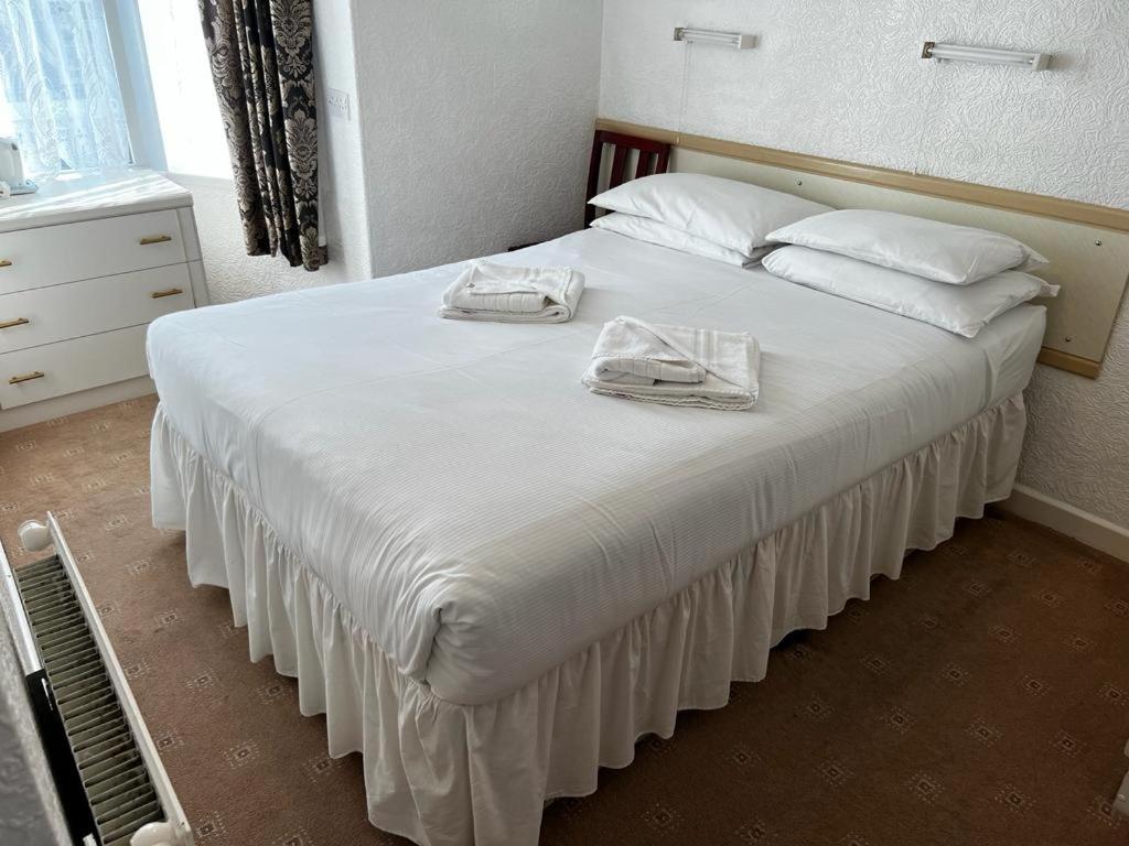 a bedroom with a large white bed with towels on it at Delton Hotel in Blackpool