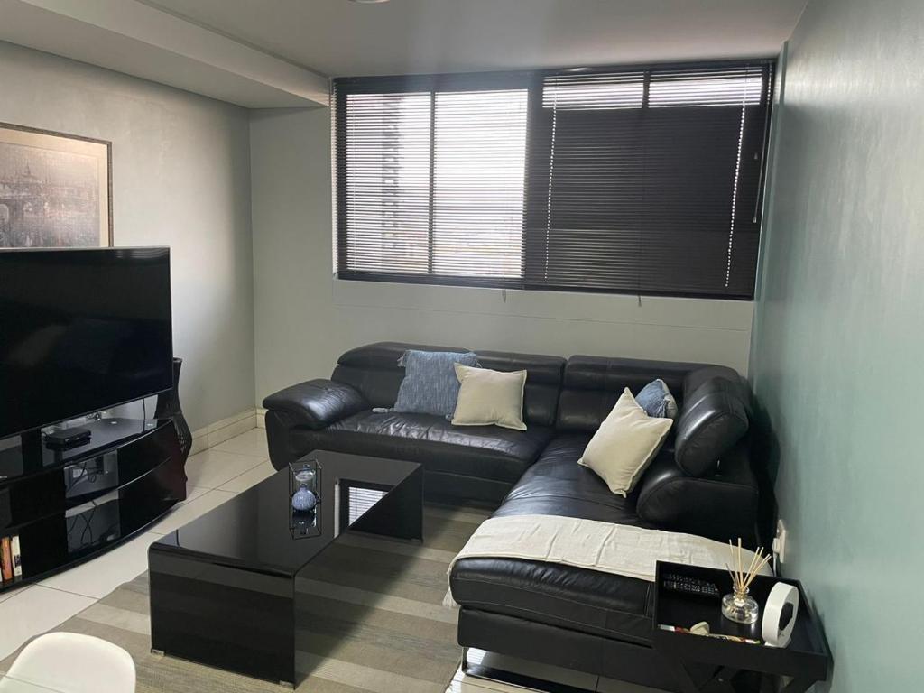 a living room with a leather couch and a flat screen tv at 104at77 Independence Street - Windhoek in Windhoek