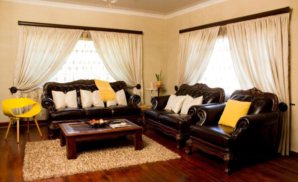 uma sala de estar com dois sofás de couro e uma mesa de centro em Cozy Blue Guesthouse em East London
