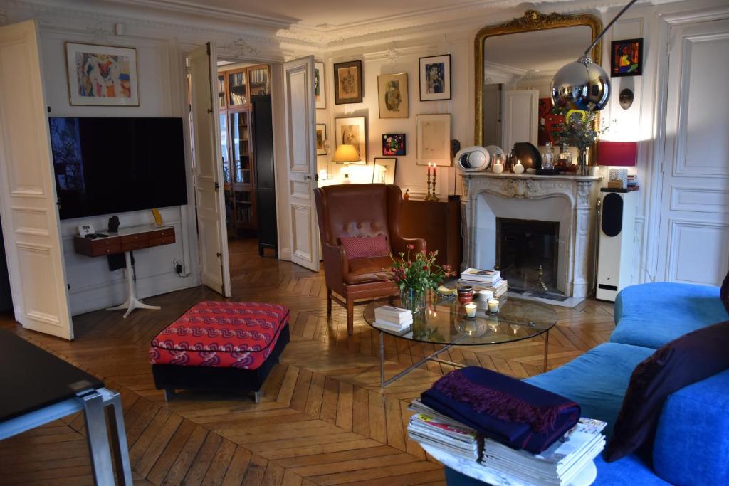 un salon avec un canapé bleu et une cheminée dans l'établissement Rue de Paradis, à Paris