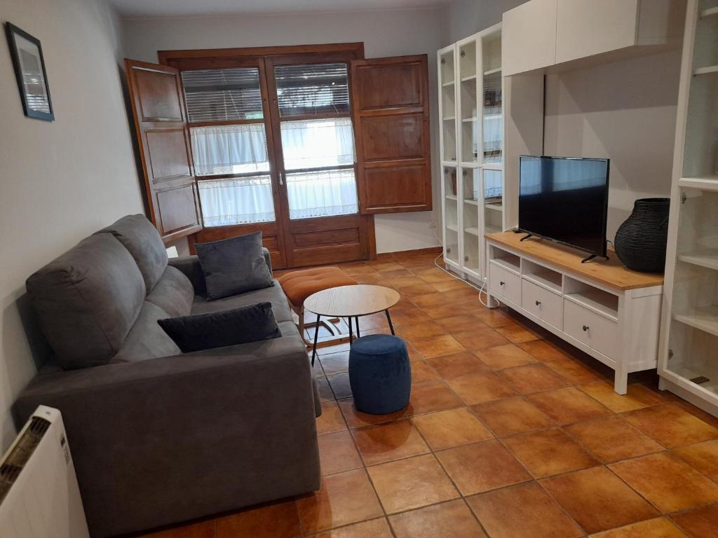 ein Wohnzimmer mit einem Sofa und einem TV in der Unterkunft Apartamento rural Muga in Sant Llorenç de la Muga