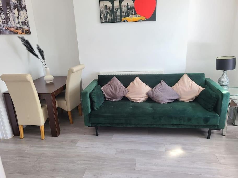 un sofá verde con almohadas en la sala de estar en Cosy 2 Bedroom Flat Newport, en Newport