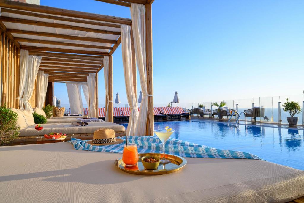 a table with a tray of food next to a swimming pool at Carlton Tel Aviv Hotel – Luxury on the Beach in Tel Aviv