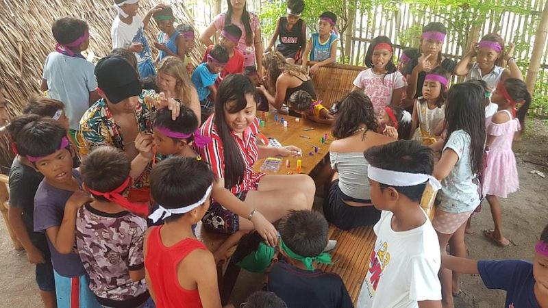 eine Gruppe von Menschen, die um einen Holztisch stehen in der Unterkunft Georgia's Neverland Hostel in Malapascua