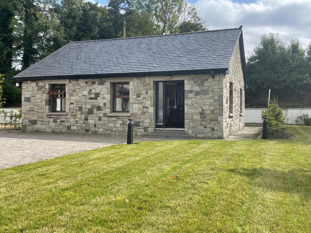 una pequeña casa de piedra con un patio de césped en Creevagh Cottage, en Castlebar
