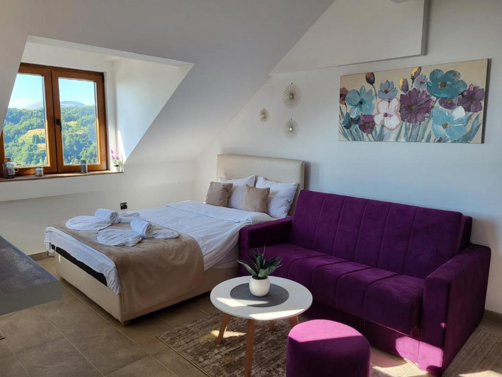 ein Bett und eine lila Couch in einem Zimmer in der Unterkunft Kloudscape Apartman Milmari Resort & Spa in Kopaonik