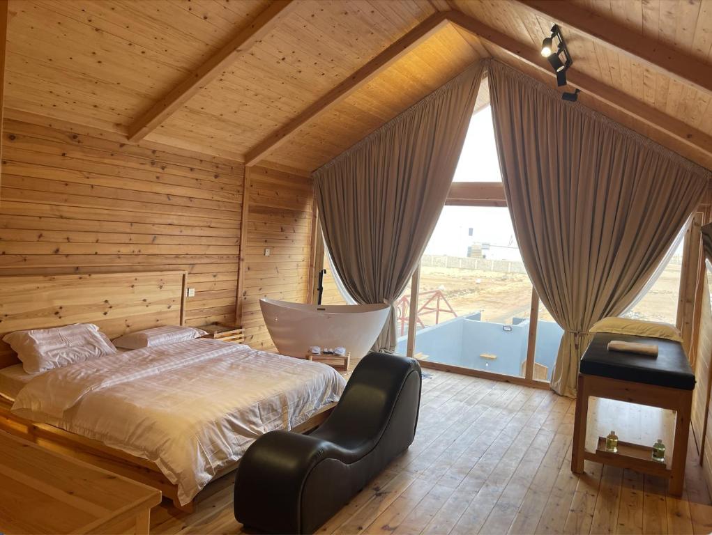 sypialnia z łóżkiem i dużym oknem w obiekcie أكواخ البحيرات w mieście Khalij Salman