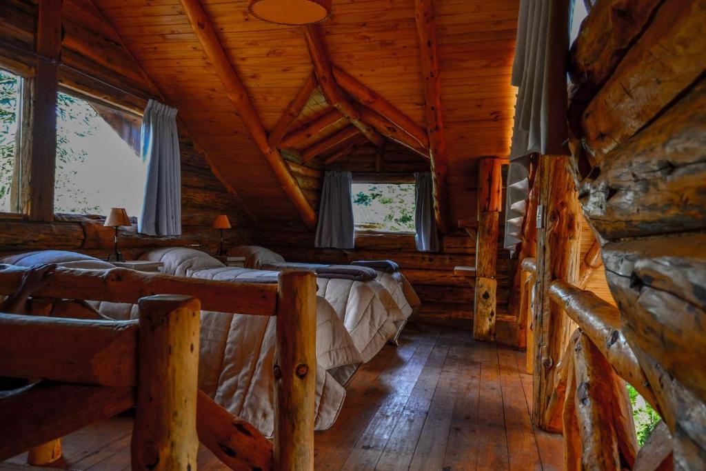 a bedroom with four beds in a log cabin at El Rincon de Pehuenia in Villa Pehuenia