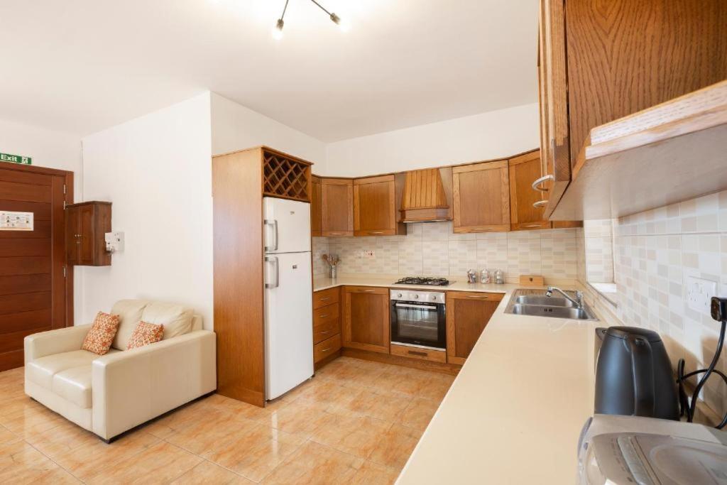 uma cozinha com armários de madeira e um frigorífico branco em Gudja - Lovely 3 bedroom unit with own private entrance em Gudja