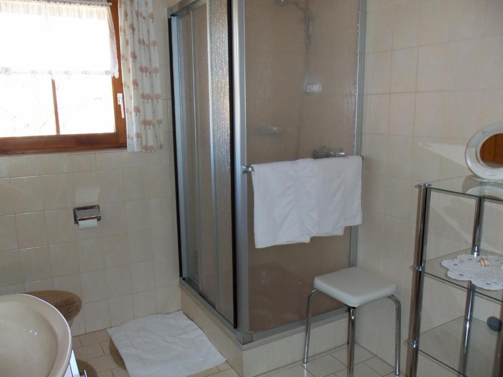 a bathroom with a shower with a stool and a sink at Wunderschöne Ferienwohnung im Haus Schupp mit bester Aussicht in Wittenschwand