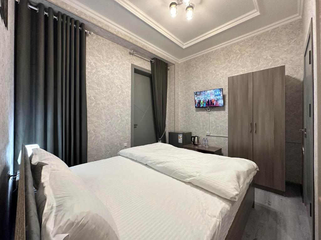 1 dormitorio con 1 cama y TV en la pared en Byond Hotel & Hostel en Tashkent