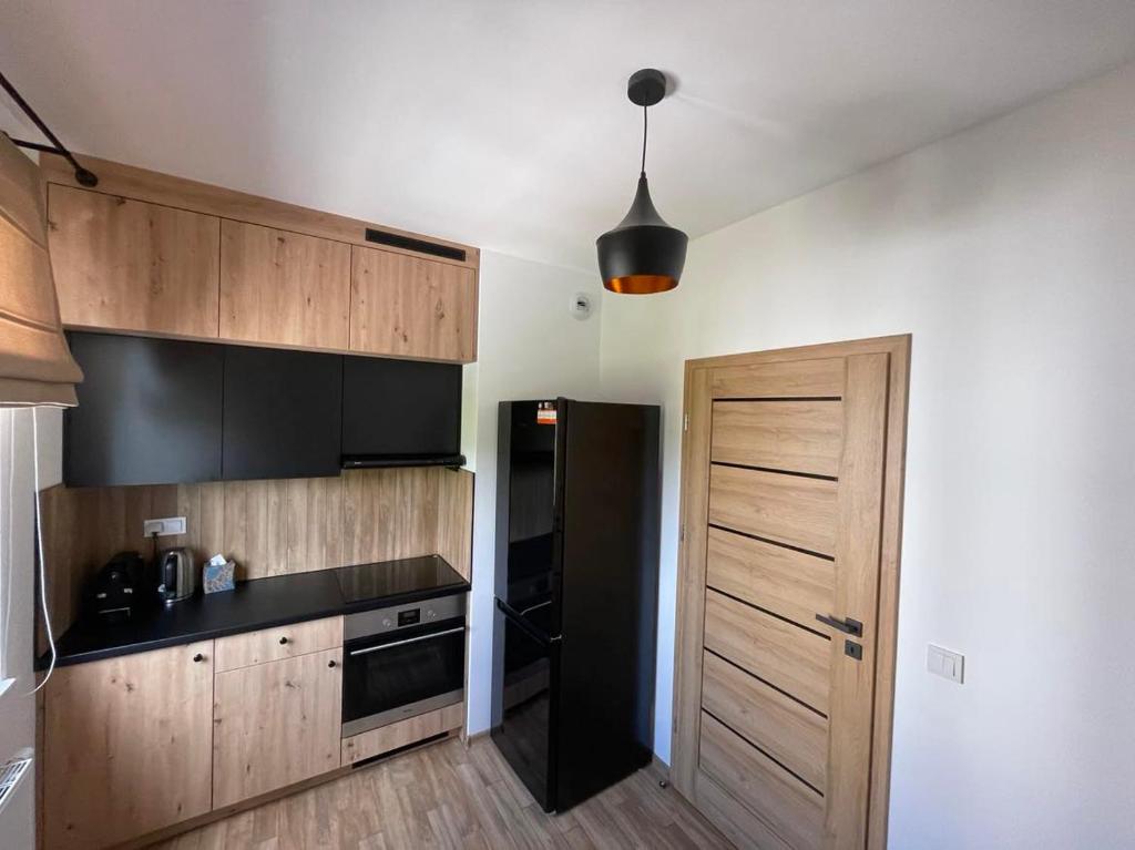 a kitchen with a black refrigerator and wooden cabinets at Airport Warsaw Mokotow Luxury Apartment in Warsaw