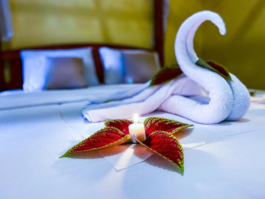 eine Kerze auf einem Bett mit Handtüchern und einer Blume in der Unterkunft Ananda Homestay Lemukih in Singaraja