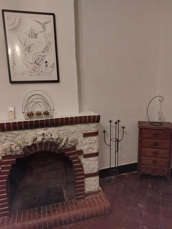 a living room with a brick fireplace with a picture on the wall at La Quiétude in Cotignac