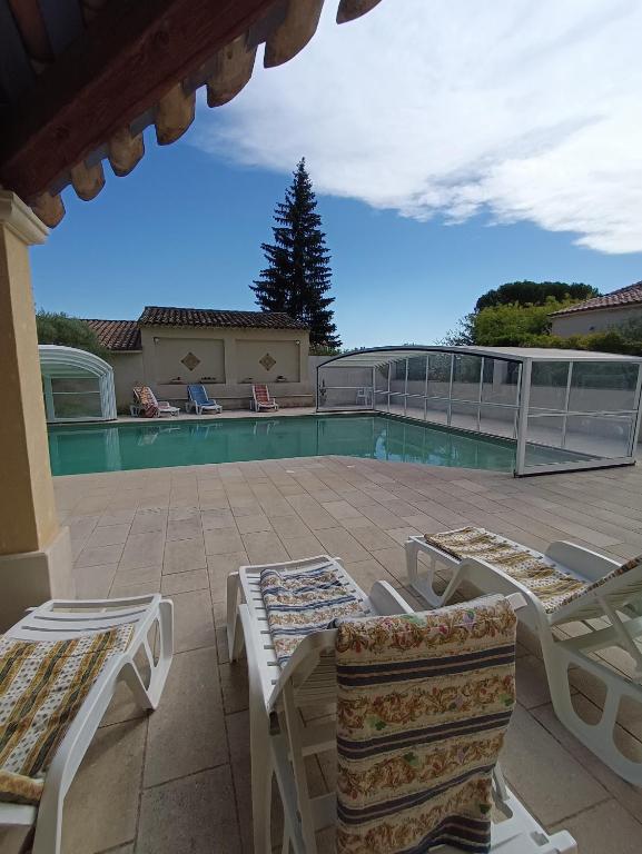 une terrasse avec des chaises longues et une piscine dans l'établissement Gîte la glycine avec piscine au mas de Saint Jean, à Saint-Romain-en-Viennois