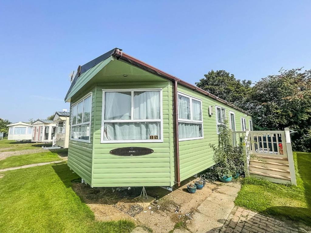 a green tiny house in a yard at Lovely Caravan For Hire With Decking At Skipsea Sands In Yorkshire Ref 41015wf in Barmston