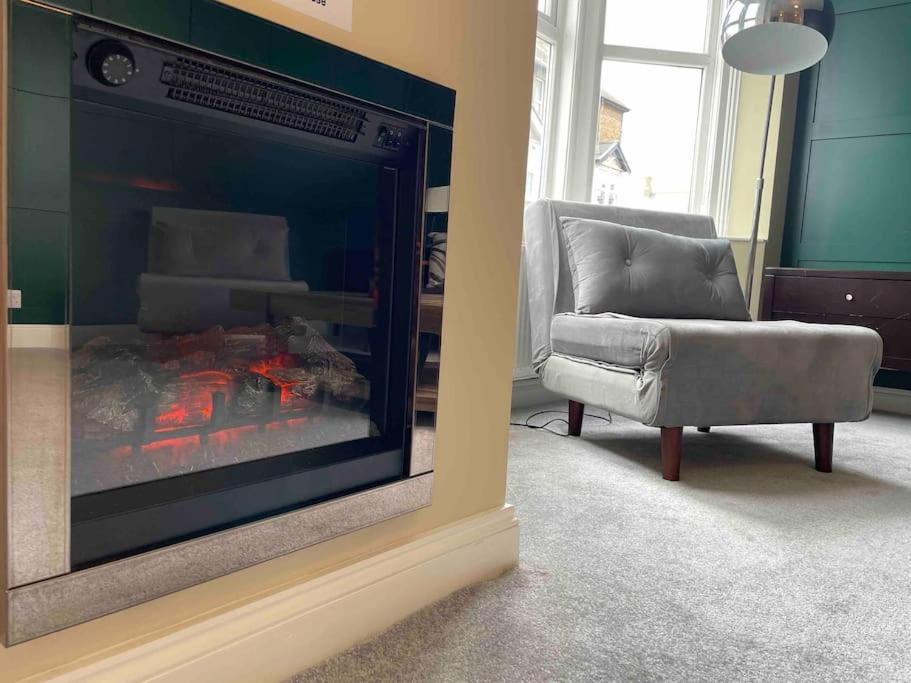 a living room with a fireplace and a chair at Stylish beachfront apartment in historic Deal in Kent