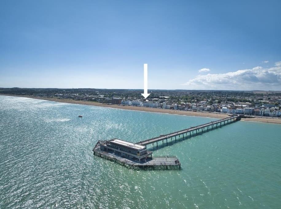 a boat in the water next to a pier at Stylish beachfront apartment in historic Deal in Kent