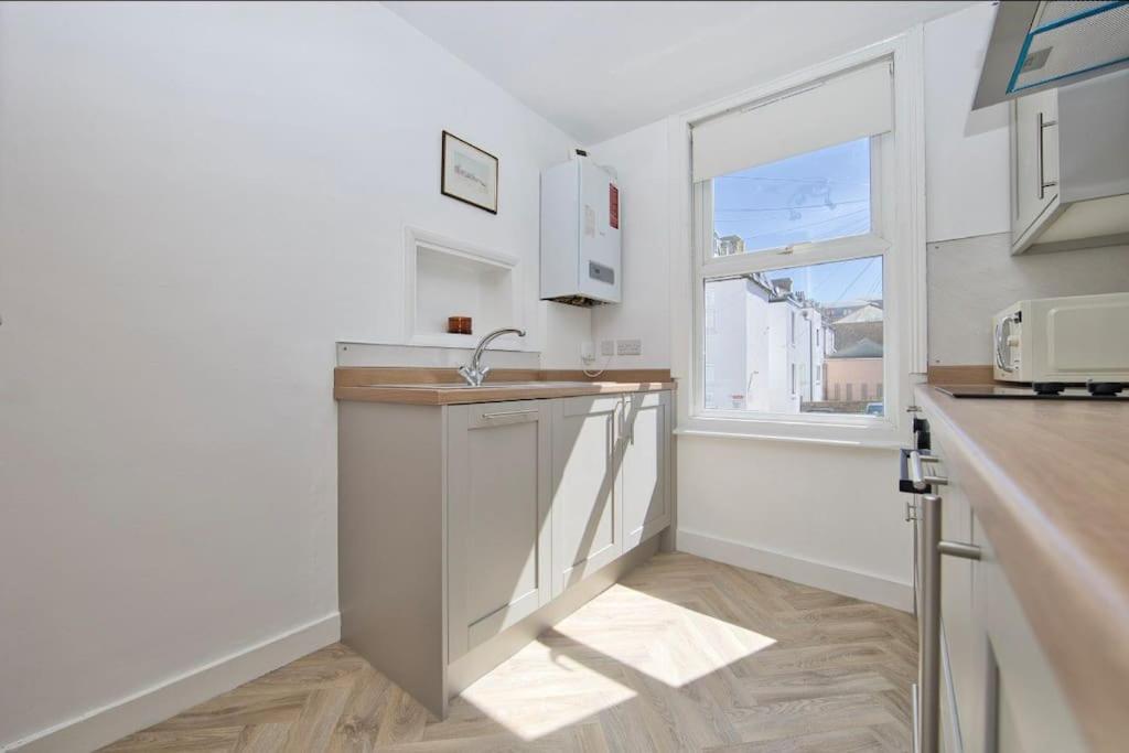 a white kitchen with a sink and a window at Stylish beachfront apartment in historic Deal in Kent