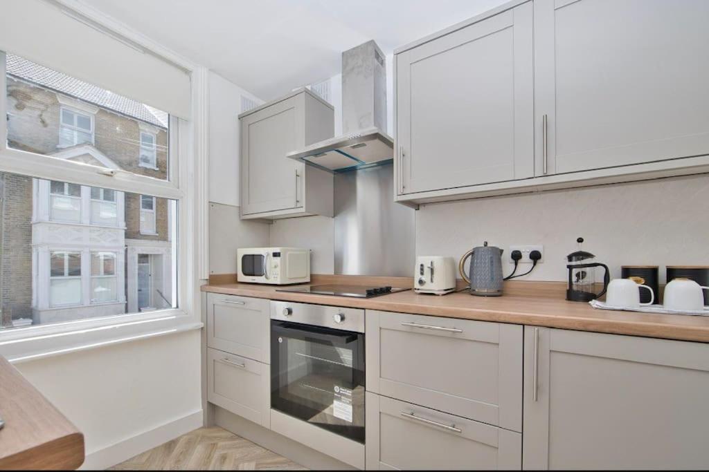 a white kitchen with white cabinets and a window at Stylish beachfront apartment in historic Deal in Kent