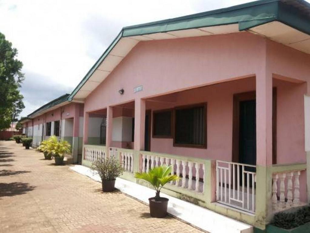 una casa rosa con macetas delante de ella en Room in Lodge - Garentiti Apartment - Silver Room, en Iyiba