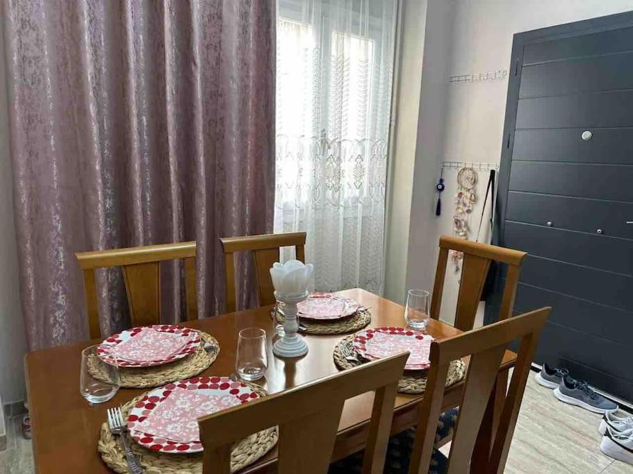 einem Esstisch mit 4 Stühlen und einem Tisch mit Geschirr darauf in der Unterkunft Frankie's House in Athen
