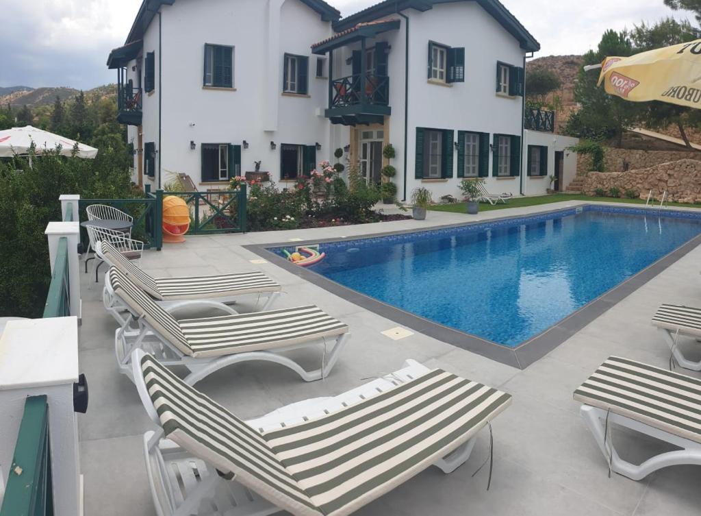 a swimming pool with lounge chairs and a house at Dervise Mehmet Guest House in Lefke-Karadağ