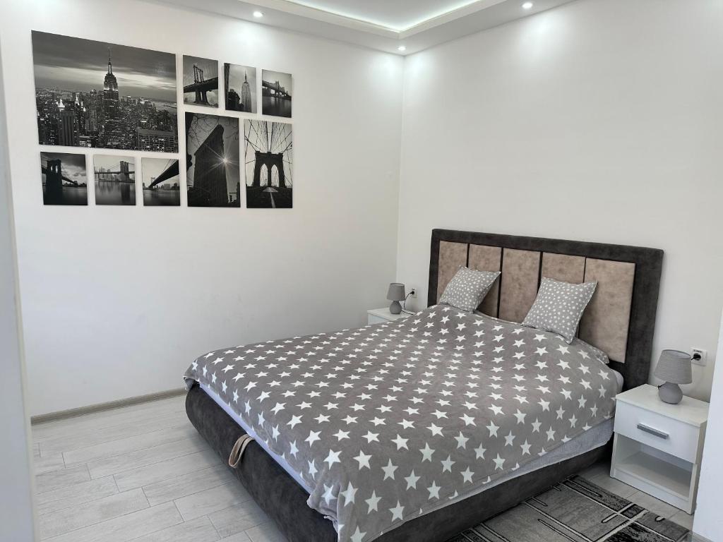 a white bedroom with a bed with a black and white blanket at Apartman Silver Star in Sombor