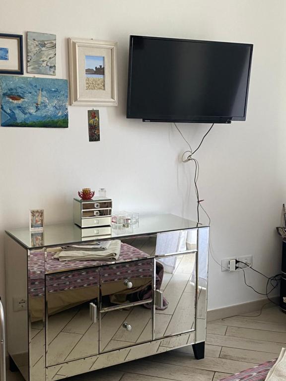 une télévision suspendue sur un mur avec un bureau dans l'établissement YONO apartment, à La Spezia