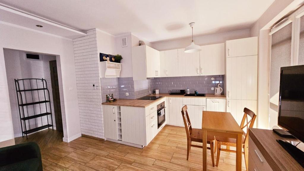 a kitchen with white cabinets and a table and chairs at Apartament Młynarska in Piła