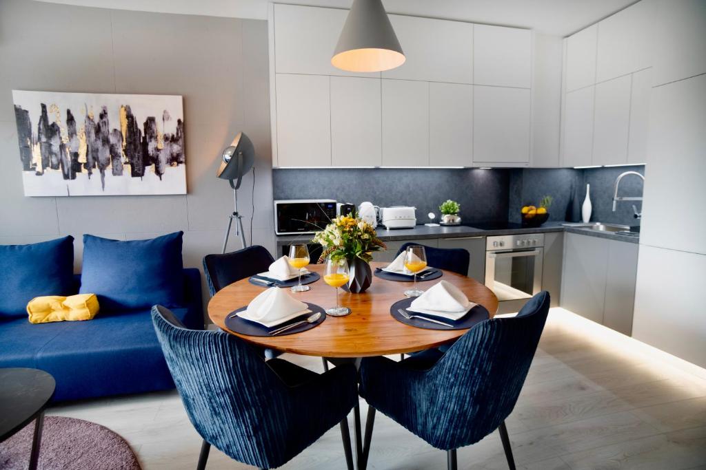 eine Küche und ein Wohnzimmer mit einem Holztisch und blauen Stühlen in der Unterkunft SuiteAngel - Luxury Design Condo with free garage in Budapest