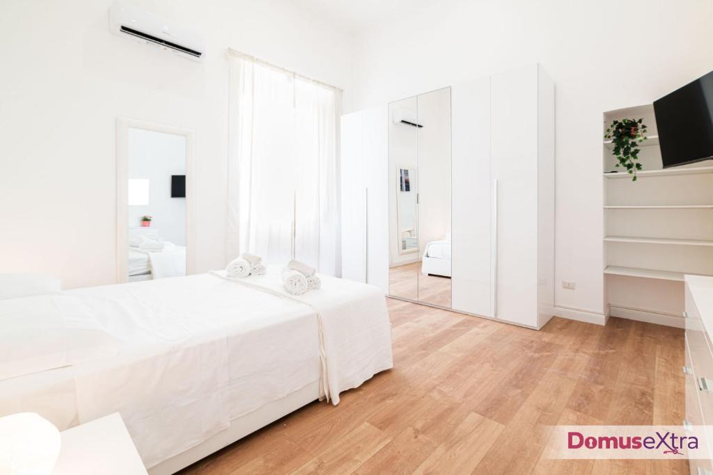 a white bedroom with a white bed and a mirror at Vanvitelli Luxury By DomusExtra in Naples