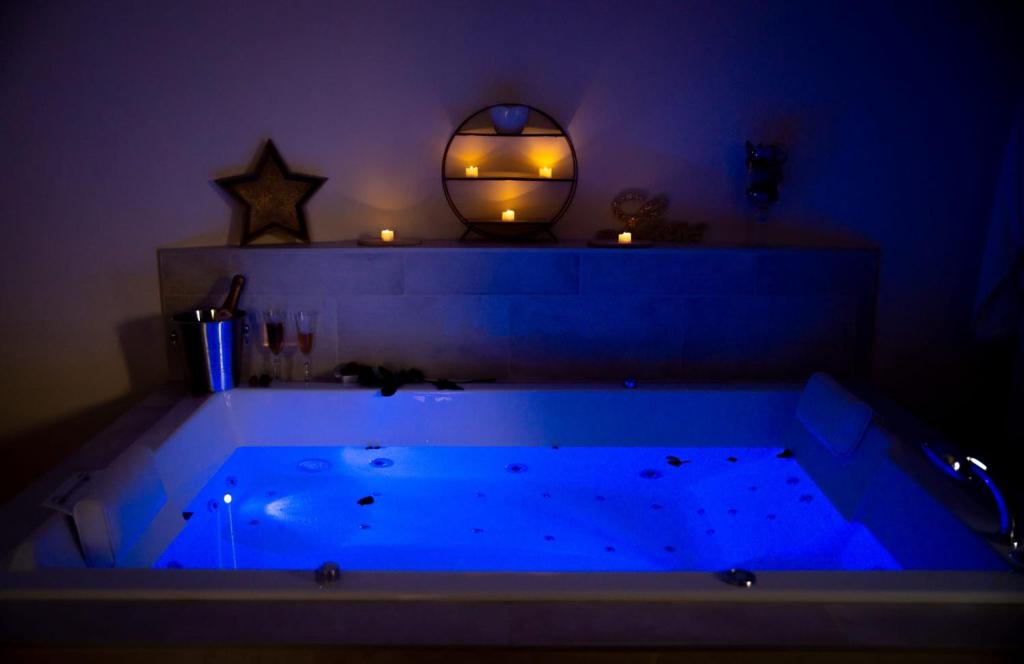 uma banheira azul num quarto com uma vela ao fundo em Le Mas aux Amoureux , Suite Romantique et Spa em Le Barcarès