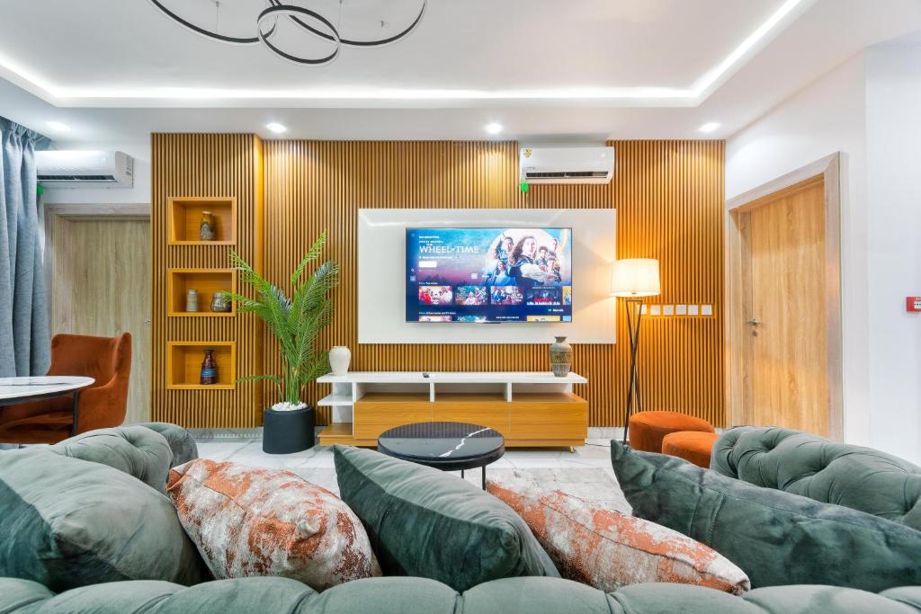 Il comprend un salon doté de canapés verts et d'une télévision à écran plat. dans l'établissement W16 Water Front Apartments, à Lekki