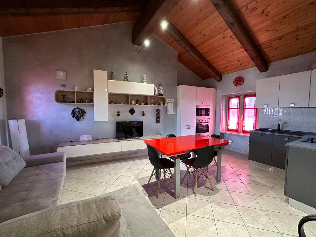 a kitchen with a red table and chairs in a room at La tana di Piozzo in Piozzo