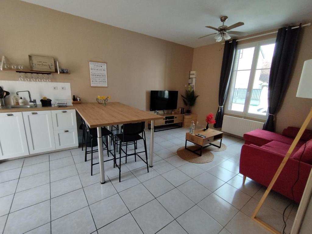 Una cocina y una sala de estar con una mesa y un sofá. en Maison de campagne proche Beauval, en Selles-sur-Cher