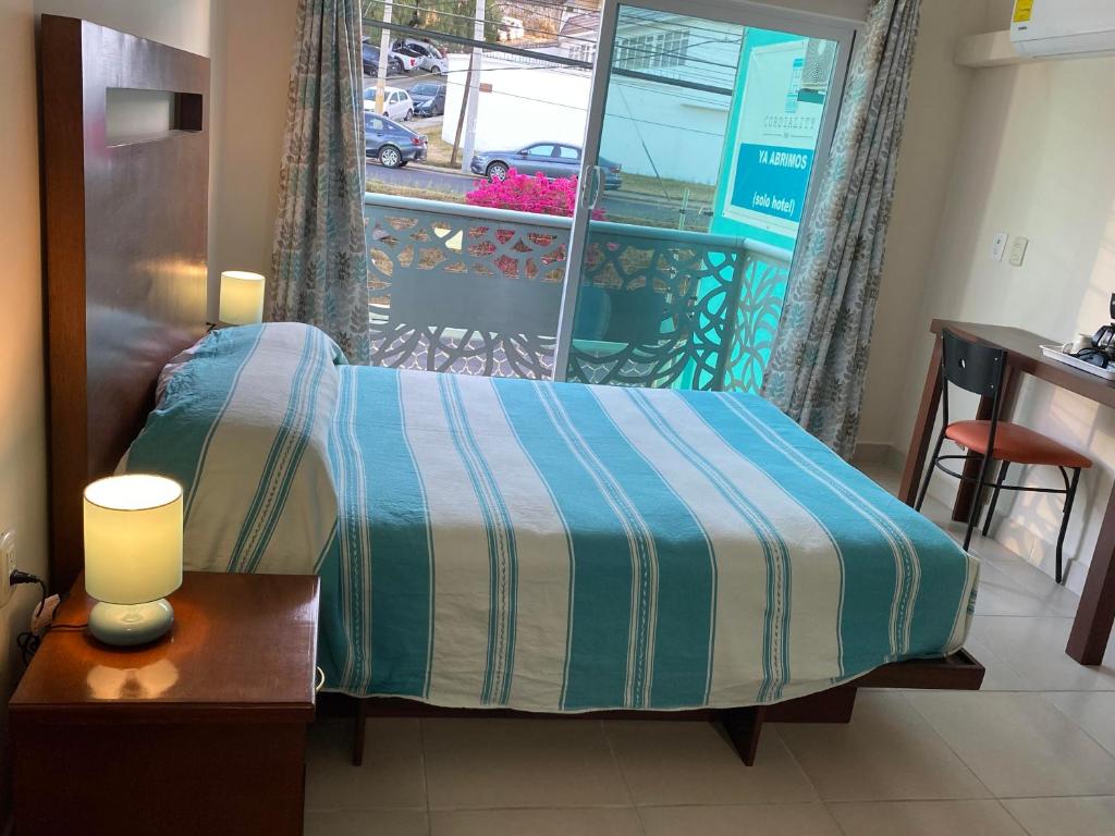 a bedroom with a bed with a table and a balcony at CORDIALITY INN in Puebla