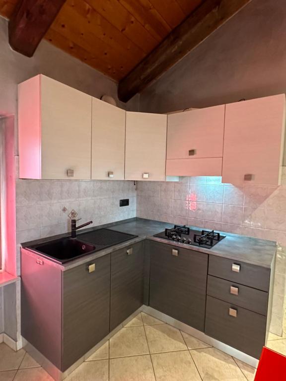 a kitchen with white cabinets and a sink at La tana di Piozzo in Piozzo
