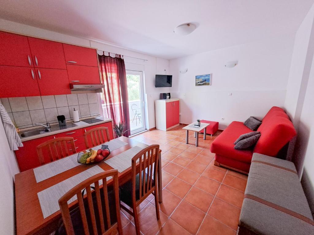eine Küche mit einem Tisch und einer roten Couch in einem Zimmer in der Unterkunft Apartment Chilly in Klek