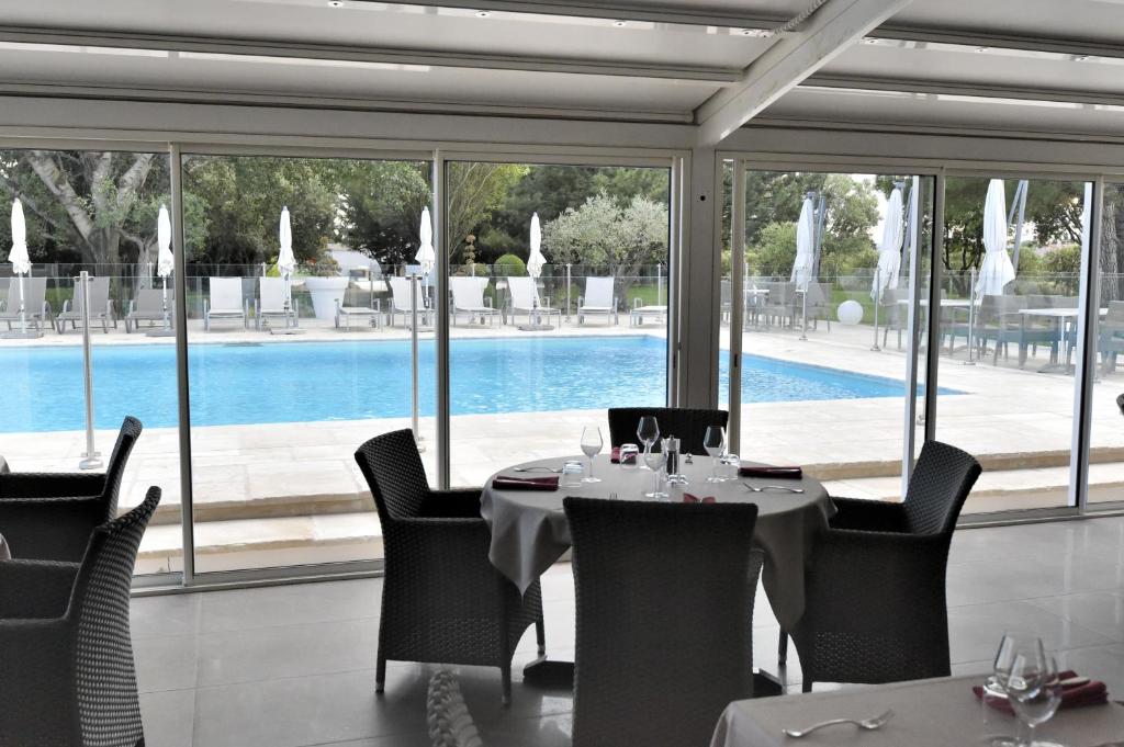 a dining room with a table and chairs and a pool at Le Domaine des Oliviers in Pierrelatte