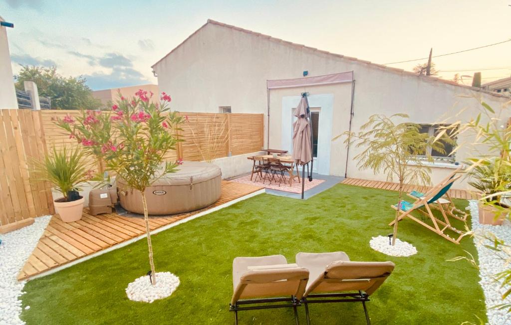un patio trasero con césped, sillas y mesa en Tiny Harmony - Logement confortable avec jardin et jacuzzi privés près d’Aix en Provence, en Venelles